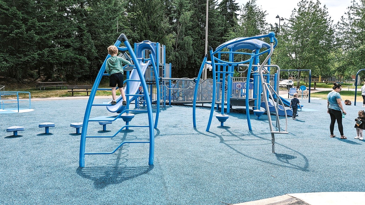 A young boy climbs on play equipment at the accessible inclusive new playground at Lynnwood, Washington's Meadowdale Playfields