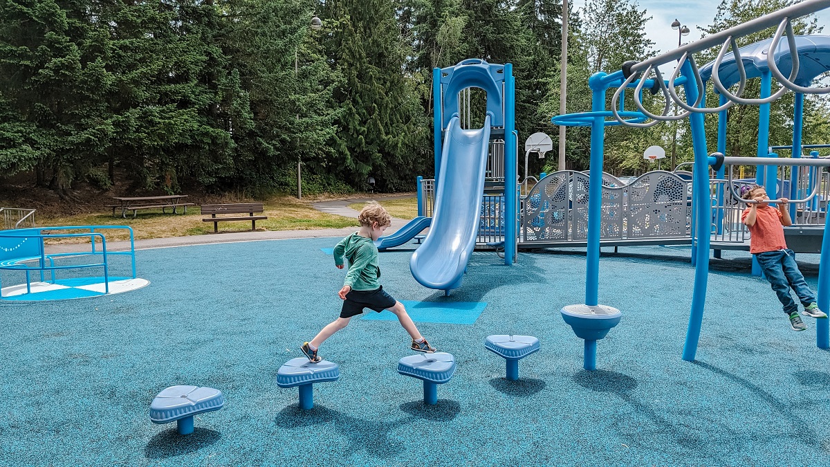 A young boy steps across wobble steps to test his balance at the new playground at Lynnwood, Washington's Meadowdale Playfields