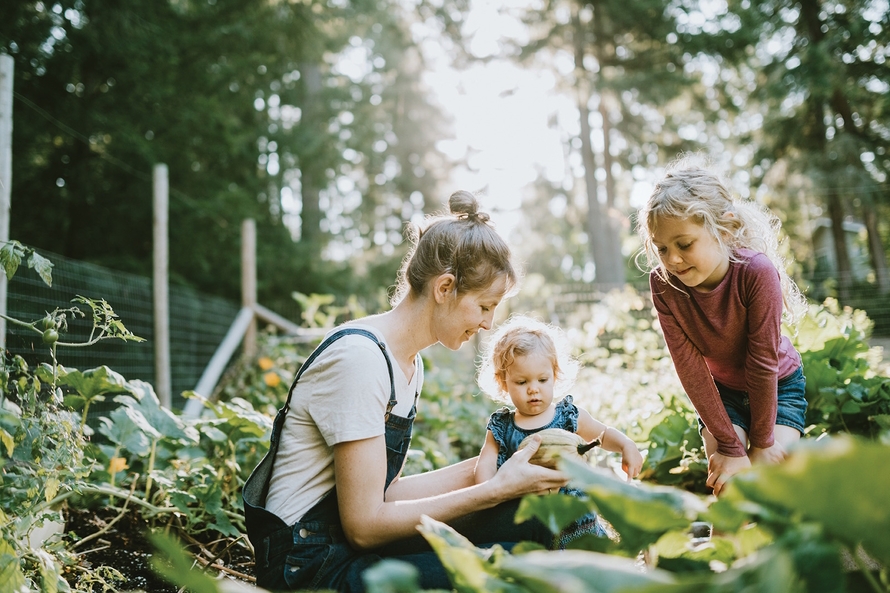 "Mom in a garden with two young children looking at a gord"