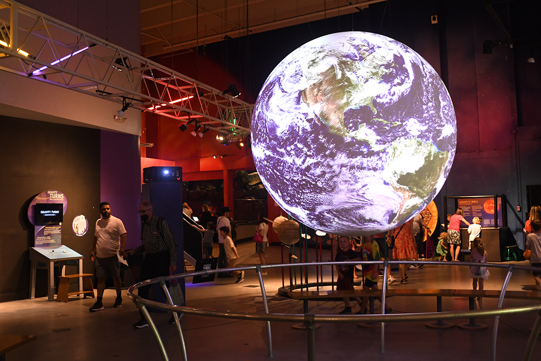 Pacific Science Center in Seattle reopens after a two and half year pandemic closure; visitors look at the Science on a Sphere exhibit