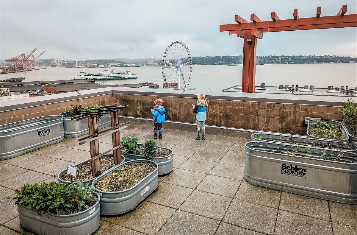 Kids watch boat traffic from the secret garden at Pike Place Market, found just past Maximilien’s patio