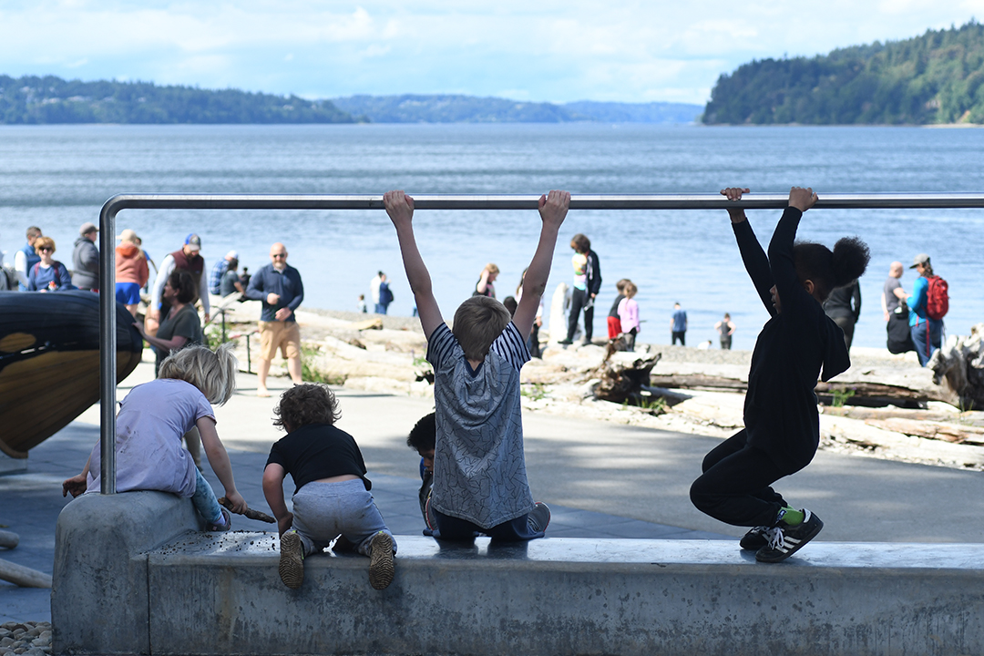 Kids play at the top of a stone slide at a new play area at Tacoma's reopened Owen Beach in Point Defiance Park