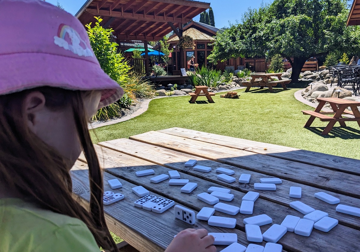 A girl plays dominoes at a picnic table at Mill Haus Cider Co. in Eatonville, Washington, after an family adventure at RailCycle Mt. Rainier
