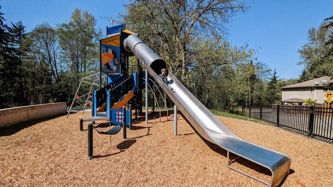 A boy descends a long metal tube slide at newly updated Salt Air Vista Park in Kent, Wash., near Seattle