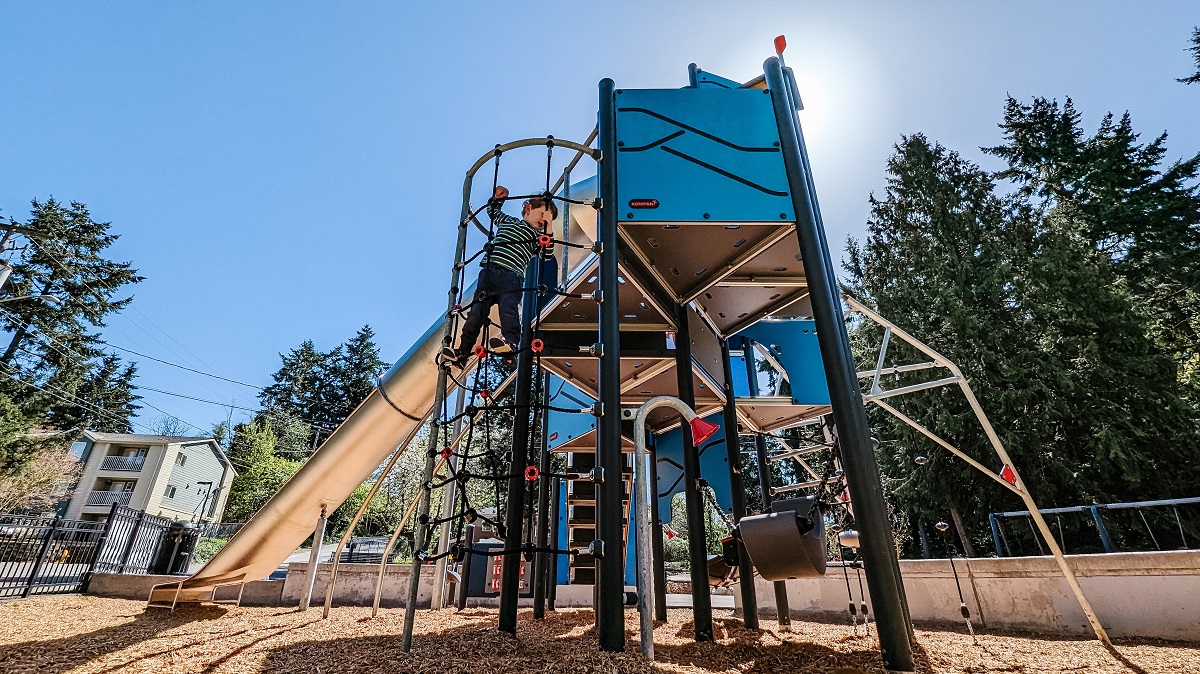A boy climbs a cargo net to the top of the climber at Kent’s Salt Air Vista Park new playground