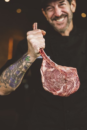 Chef Scott Letourneau holds a tomahawk steak