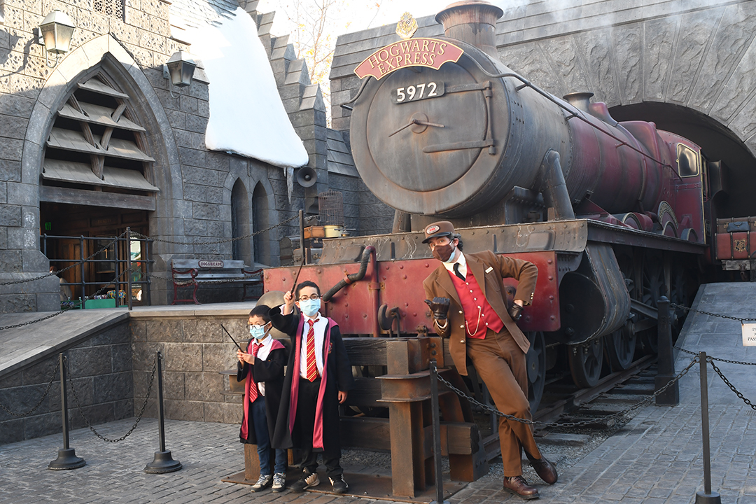 Two boys and a train engineer post in front of the Hogwarts Express at Universal Studios Hollywood Wizarding World of Harry Potter best tips for families