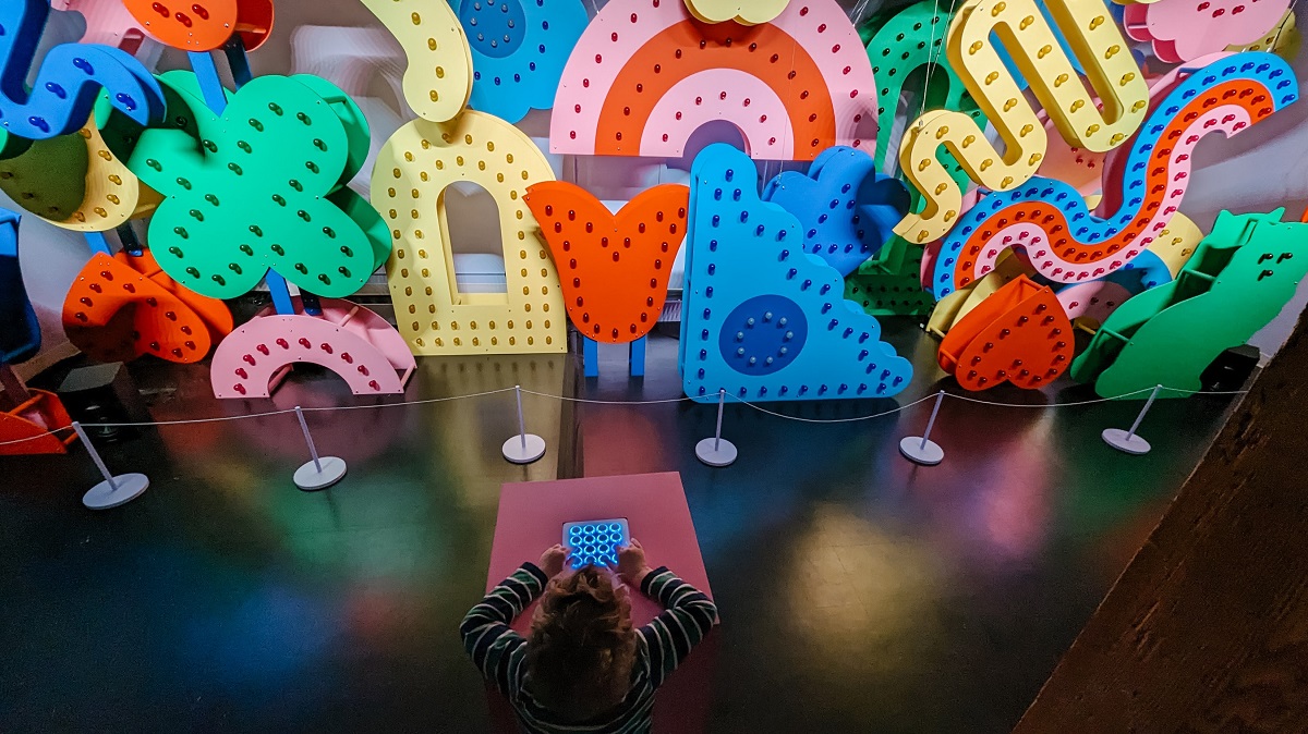 A young boy operates the interactive color shape and music art installation at WNDR Seattle