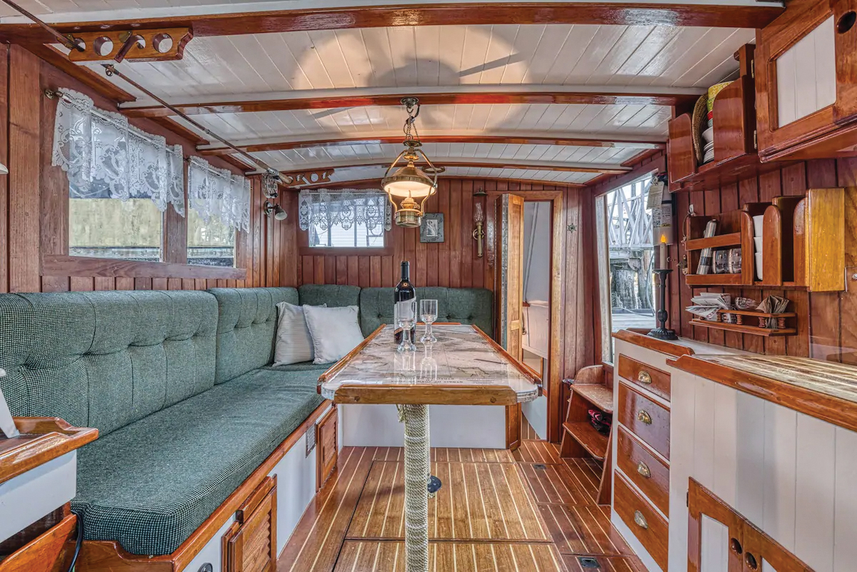 "inside of a houseboat with a bottle and two wine glasses on a marble top table"