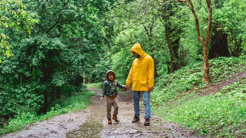 "Dad and son on a path in the woods on a rainy day hiking"