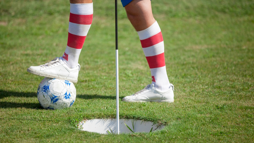 "A foot and leg with a red and white striped sock playing footgolf"