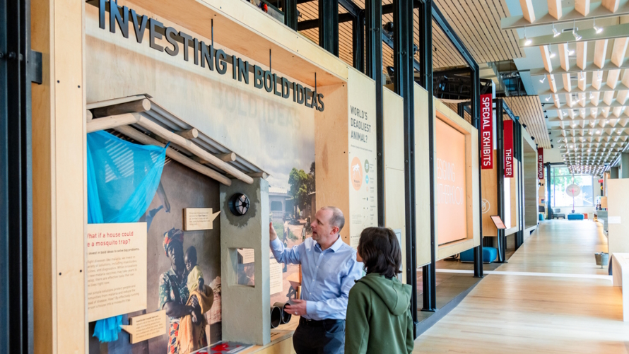 "a man and child learning about the new exhibit at the Gates Foundation Discovery Cetner"