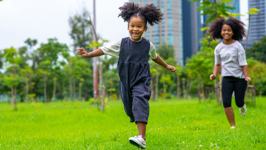"Little girls running in a green grass field"