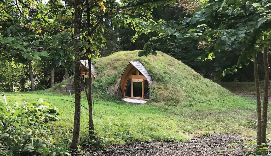 A "hobbit" house built into the earth, surrounded by trees