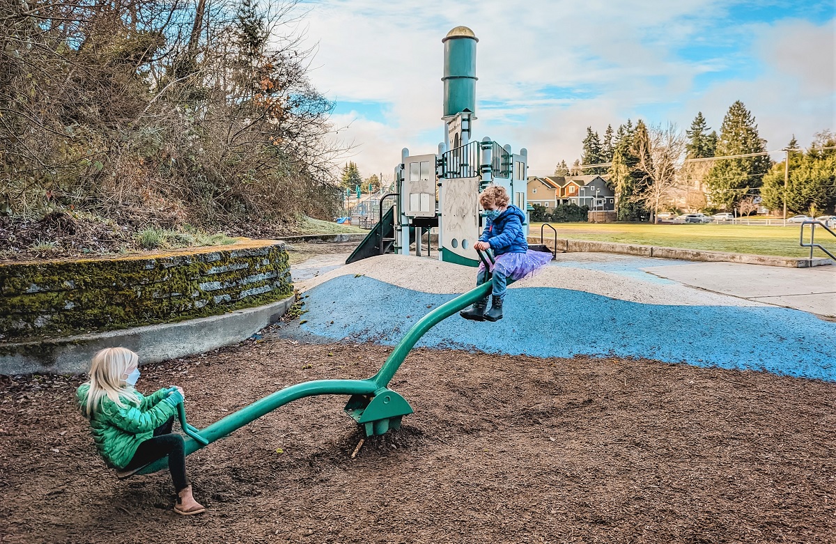 Two kids play on the old-school seesaw teeter-totter at West Seattle’s Fairmount Playground recently updated but with some legacy features preserved