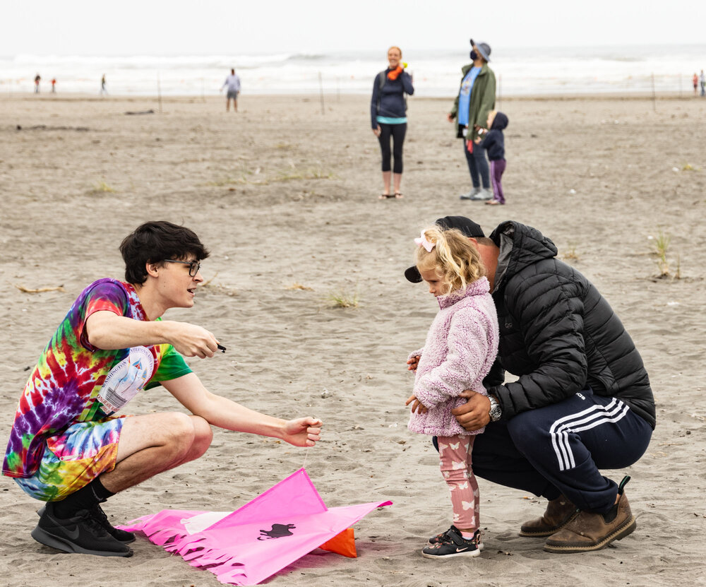 "Kids at the beach getting ready to fly a kite"