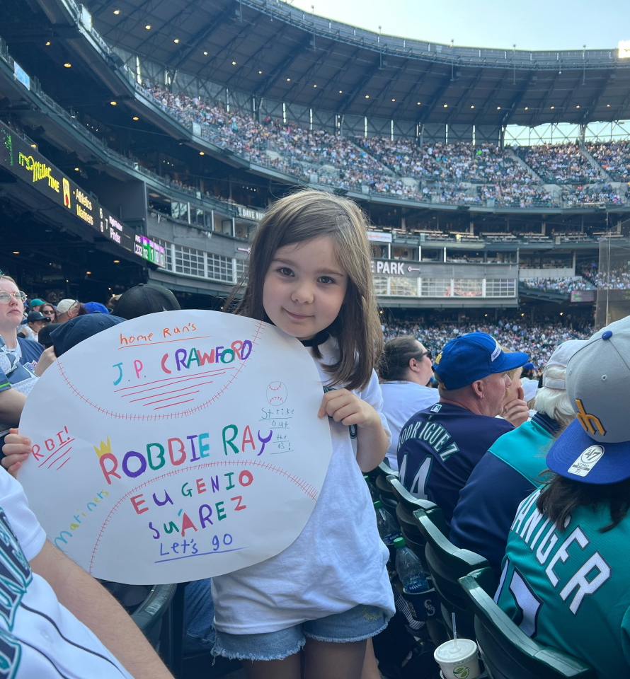 "Young girl holding a homemade sign at a Mariner's baseball game"