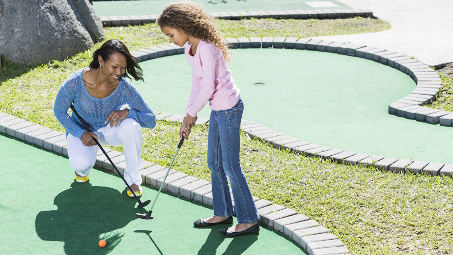 "Mom and daughter playing minigolf one on one time together"