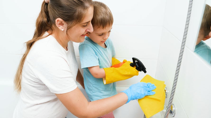 "Mom and son using eco-friendly cleaning products to clean a shower"