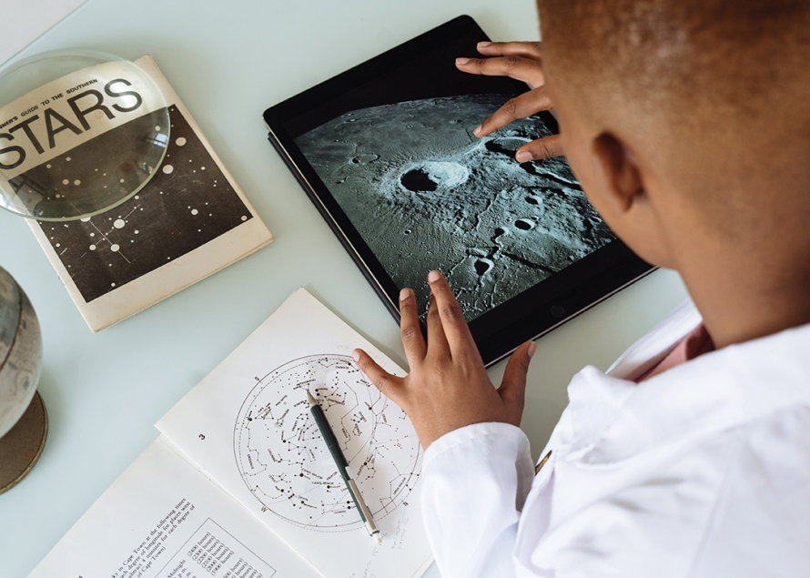 "Boy using a tablet to look at an image of the moom"