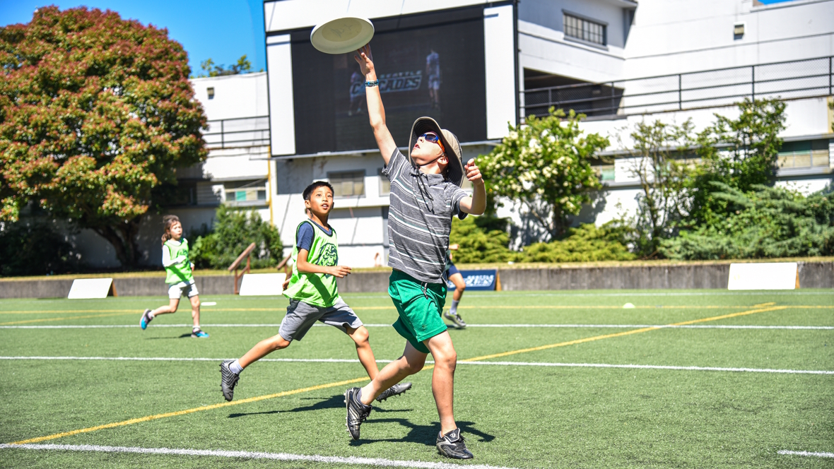 "Kids playing Seattle Ultimate Frisbee reaching for the disc"