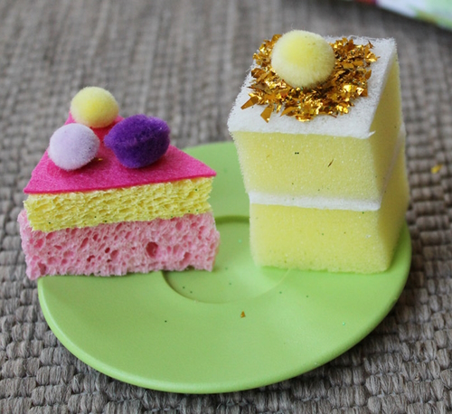 "Two pieces of pretend cake made out of pink and yellow sponges" 