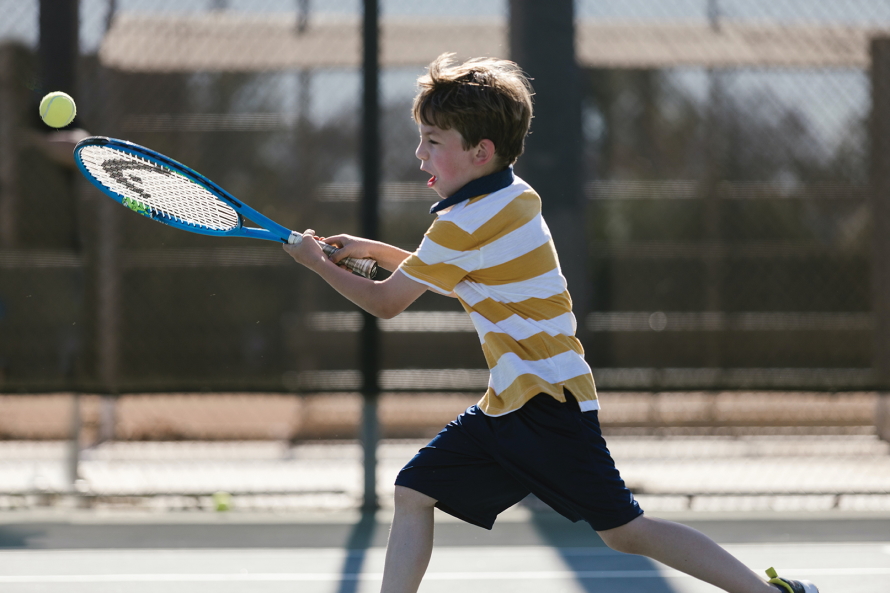 "Young boy playing tennis"