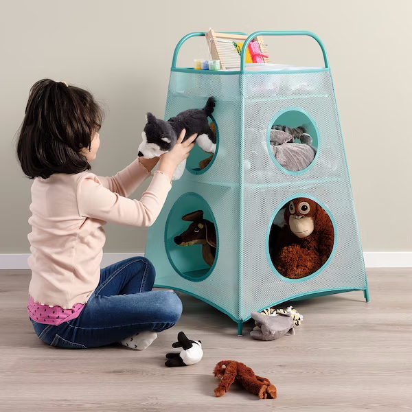 "Young girl sitting on the floor putting toys into a storage tower"