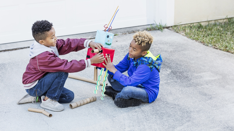 "two boys building robot out of cardboard at an eco-friendly birthday party"