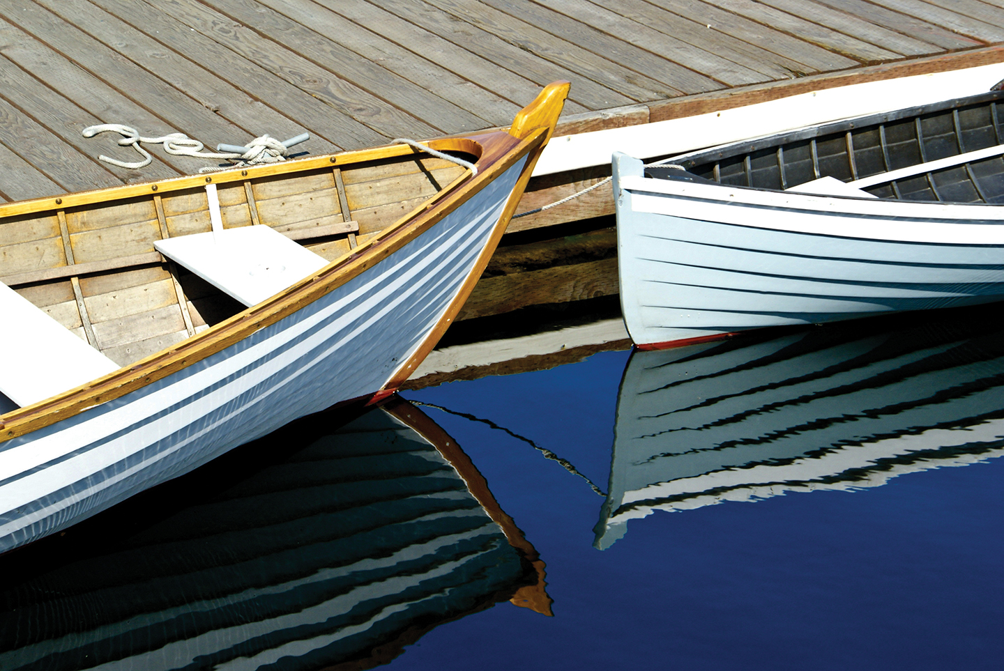 "Two wooden boats floating on the water near a dock"