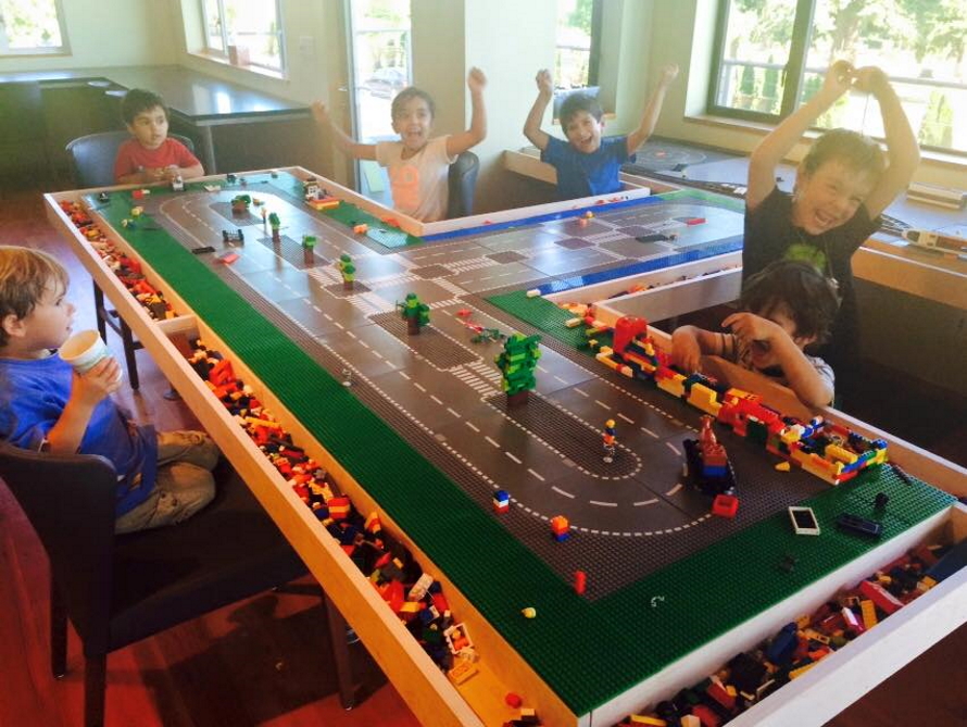 ""Kids sitting at a lego table cheering