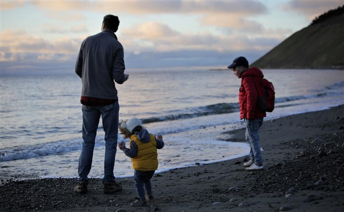 Dad and kids playing on a Washington beach before sunset with bluffs in the background 1,000 hours outside challenge