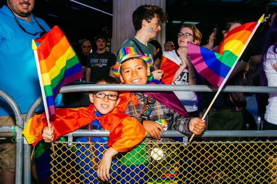 Kids wave rainbow flags at a Seattle Pride event, along the Pride Parade in Seattle route