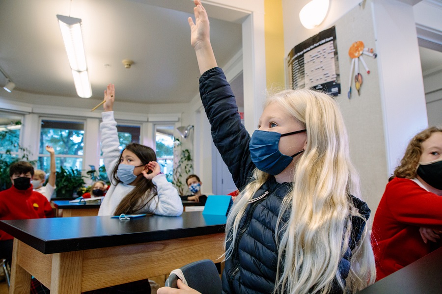 A middle school student at Seattle's Epiphany School raises her hand in class
