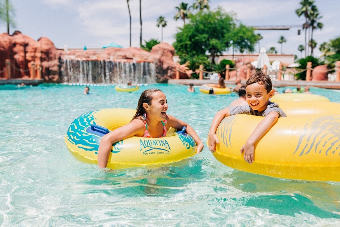 Kids in inner tubes laughing and enjoying the pool at sunny Arizona Grand Resort and Spa water park best sunny destinations one flight from Seattle