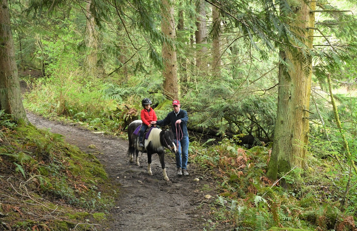 Boy on a pony ride with his dad along side on foot at Lang’s Pony Farm in Mount Vernon, Wash.