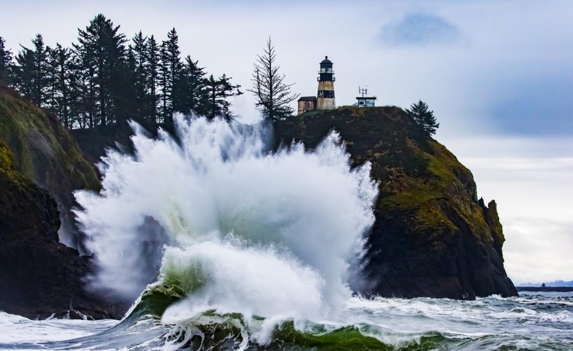 A huge wave crashes against the rocks at Cape disappointment state park in southwest Washington among great storm watching destinations for seattle families