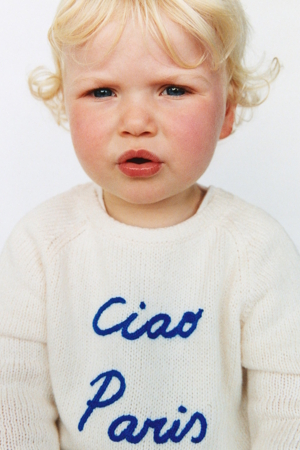 chid wearing a white sweater that says "Ciao Paris"