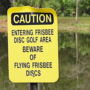 sign at a disc golf course warning of flying discs