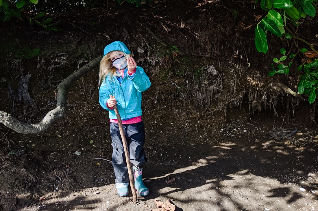 Young girl in blue jacket standing outdoors near Seattle's Lower Duwamish Watereway holding up a shell during Duwamish ecotour