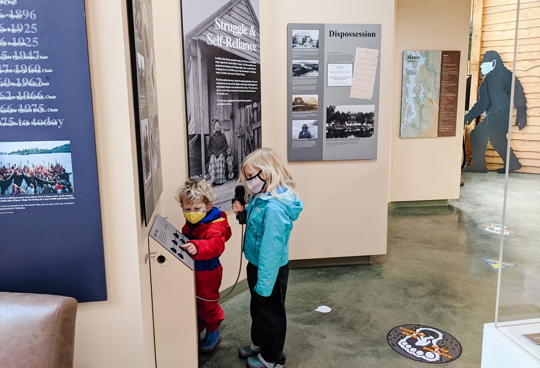 Two young kids inside the Duwamish Longhouse in Seattle looking at exhibits before an ecotour offered by the Duwamish tribe