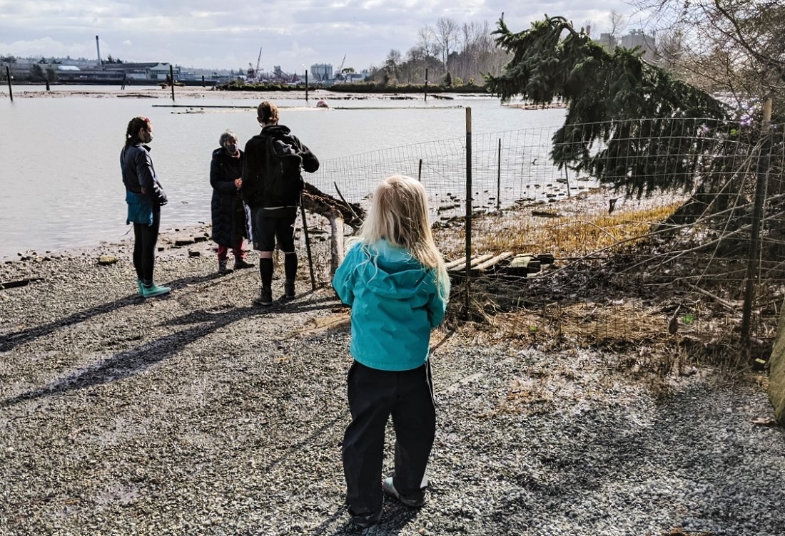 Group of tour participants standing on the shore of Seattle's Lower Duwamish Waterway on a Duwamish tribe ecotour