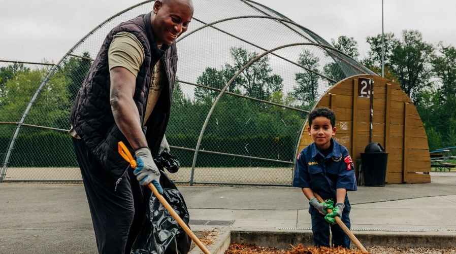 A cub scout and leader help beautify a park during an Earth Day event.