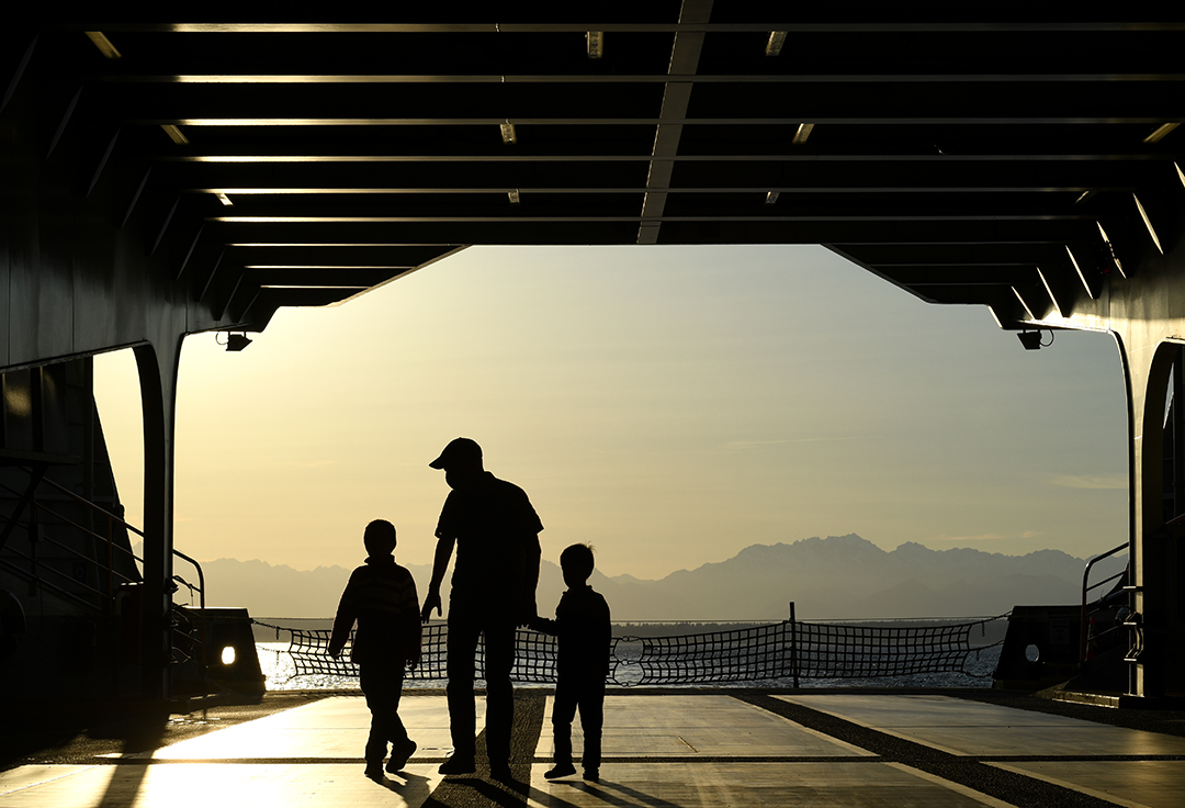 Dad and boys on the car deck on a Washington State Ferry at sunset returning from Olympic Peninsula getaway