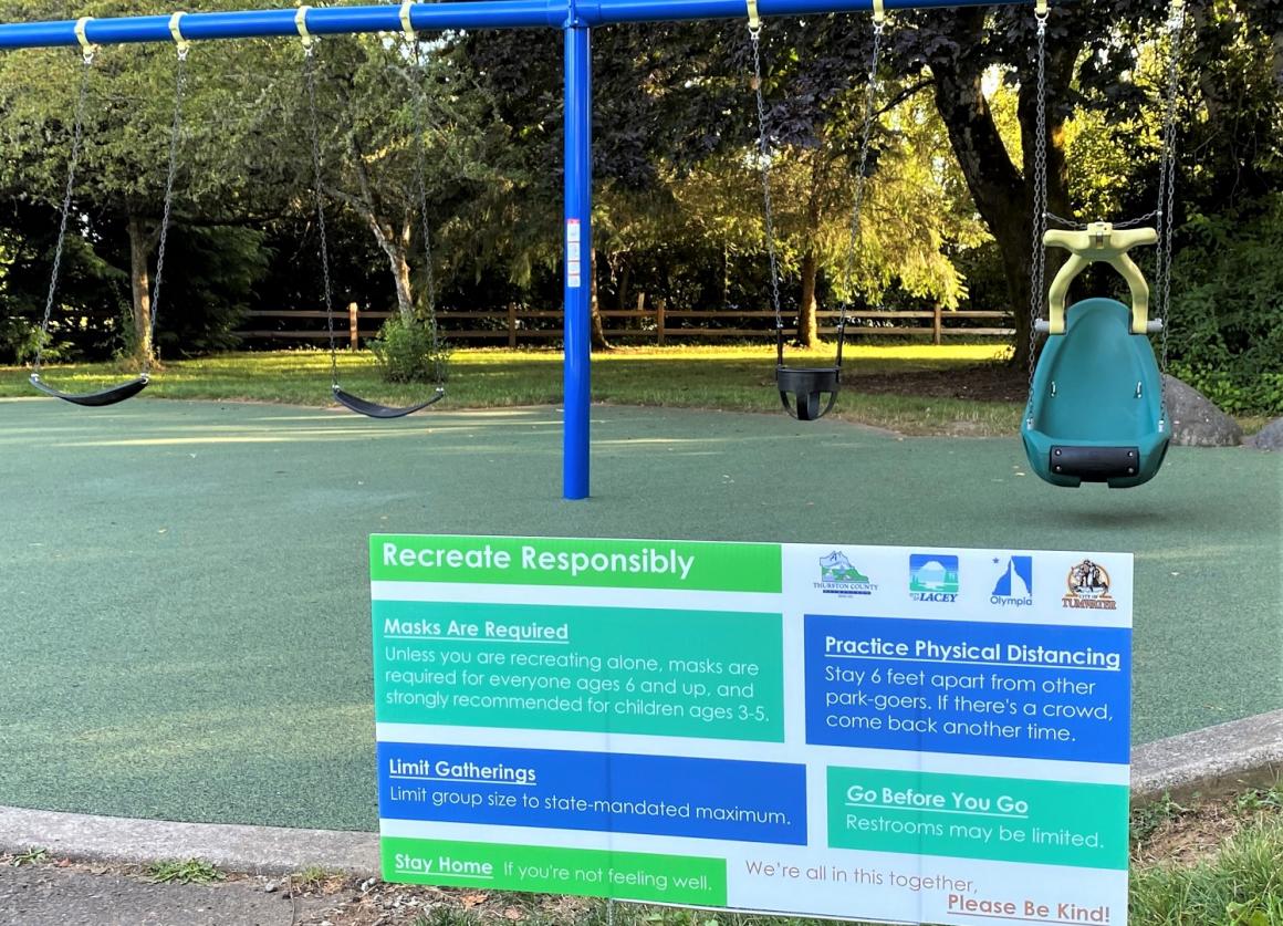 swings and a sign explaining rules at new Friendly Grove playground in Olympia