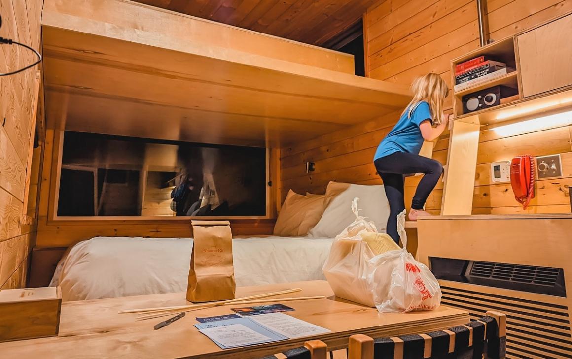 A young girl climbs the ladder to the loft bed inside a tiny cabin at Getaway Skagit Valley on a family vacation from Seattle