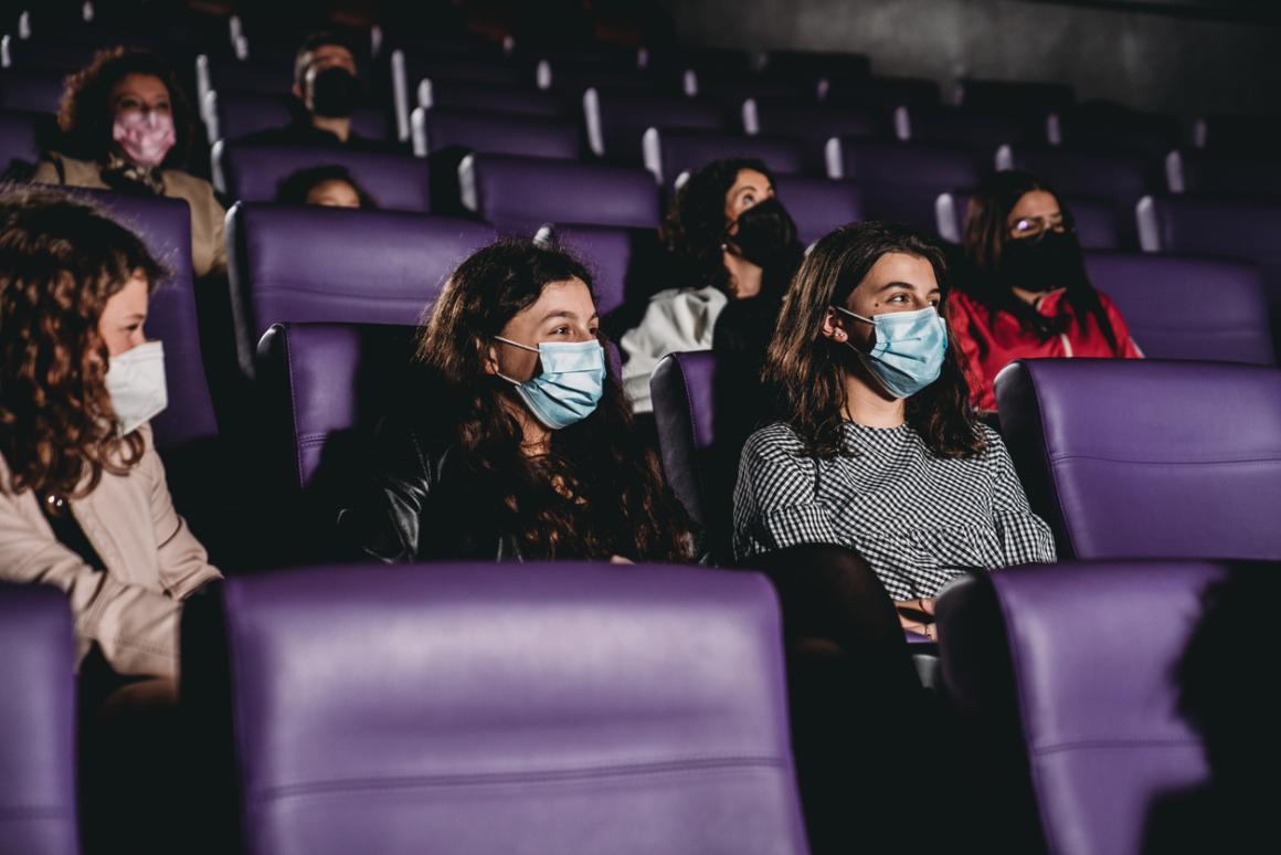 Teen girls wearing masks for covid-19 in a movie theater staying cool during a seattle heat wave air conditioning