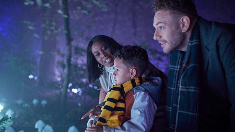 Boy wearing hufflepufff scarf with parents on either side at Harry Potter experience in Vancouver, B.C.