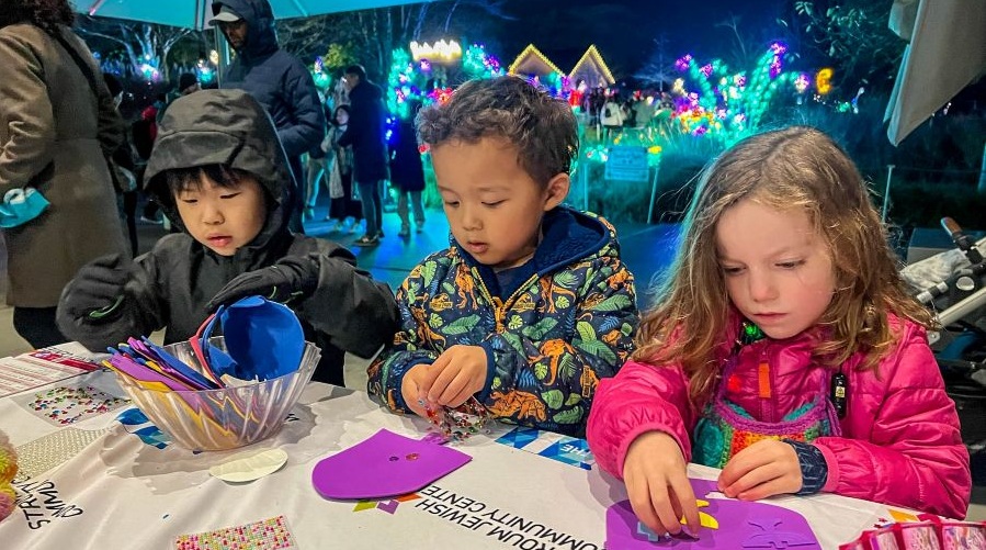 Two boys and a girl make Hanukkah crafts at a hands-on Hanukkah event.