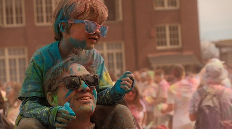 A boy and his father are covered in colors at a Holi celebration in Seattle.
